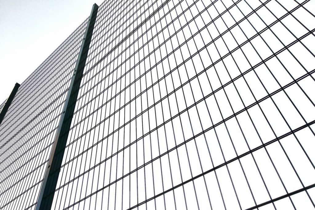 High wire mesh fence in restricted area on blue sky background